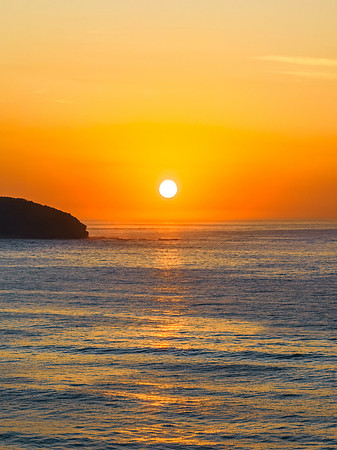 Soft hazy sunrise seascape with full sun and orange horizon