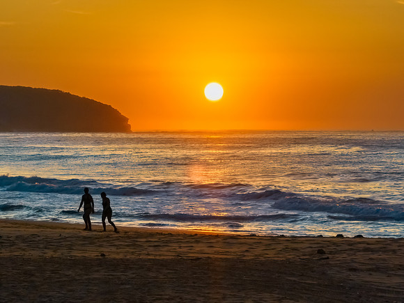 Soft hazy sunrise seascape, orange sky, people silhouettes and f