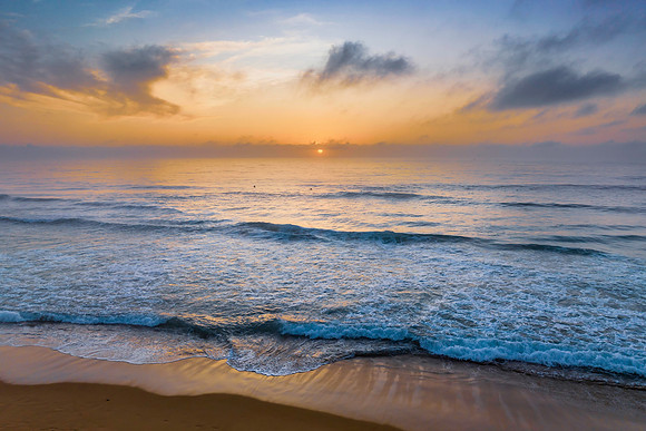 Summer sunrise at the seaside with clouds and haze