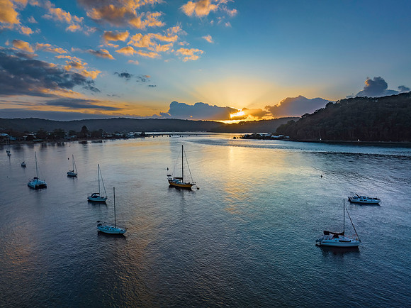 Sunrise over the water with clouds and boats