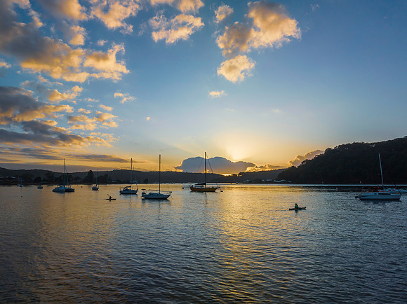 Sunrise over the water with clouds and boats