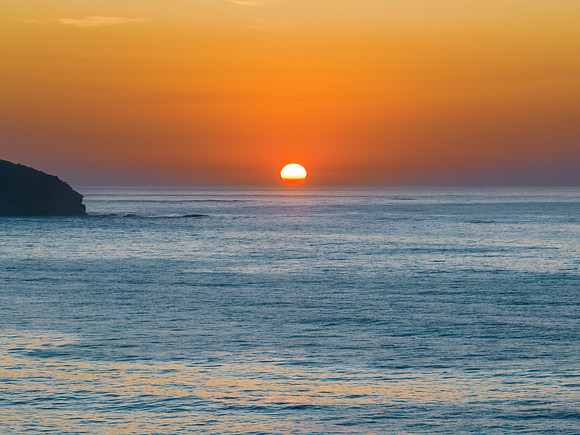 Soft hazy sunrise seascape with full sun and orange horizon