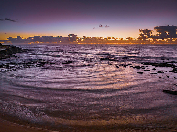 Summer sunrise at the seaside with clouds and rocks