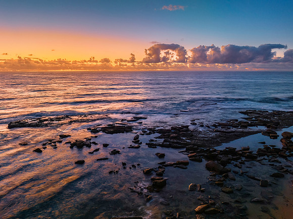 Summer sunrise at the seaside with clouds and rocks