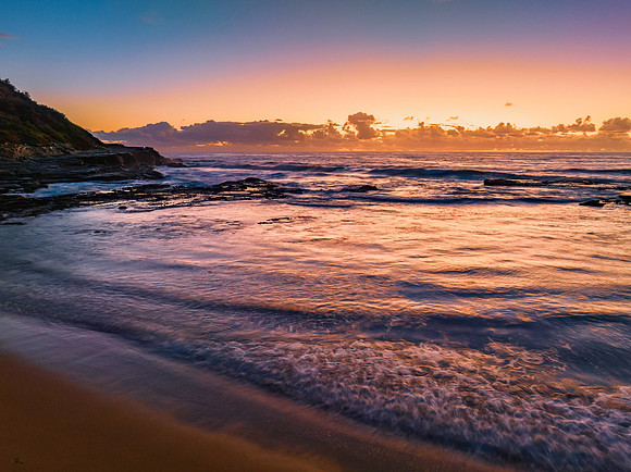 Summer sunrise at the seaside with clouds and rocks