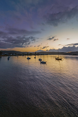 Sunrise over the water with clouds and boats