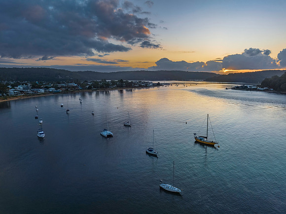 Sunrise over the water with clouds and boats
