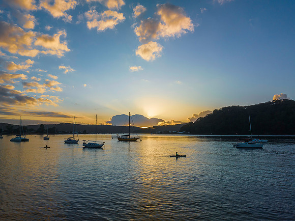 Sunrise over the water with clouds and boats