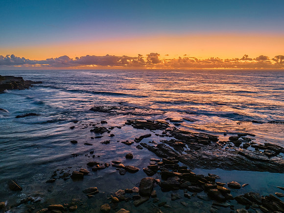 Summer sunrise at the seaside with clouds and rocks