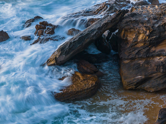 Top down sunrise at the seaside with rocks, waves and swirls