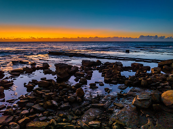 Sunrise over the sea and rocky Inlet with clear skies and a low