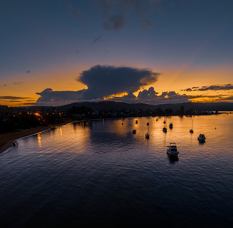 Aerial sunrise waterscape with scattered rain clouds, fog and bo