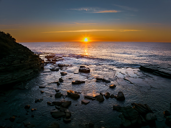 Sunrise over the calm sea and rocky Inlet