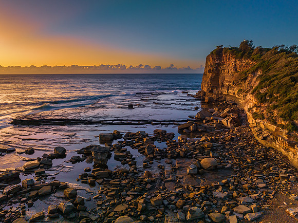 Sunrise over the sea and rocky Inlet with clear skies and a low