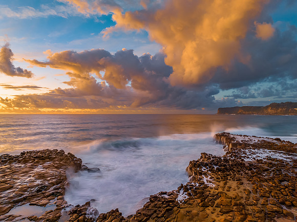 Sunrise and clouds over the ocean and rock platform