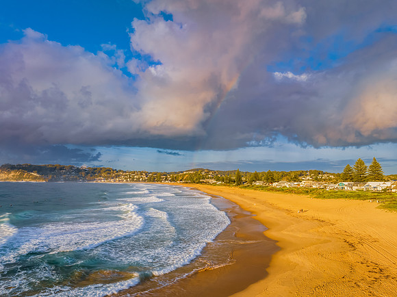 Early morning views at the beach with clouds and a rainbow