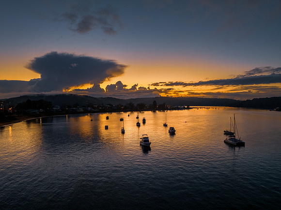 Aerial sunrise waterscape with scattered rain clouds, fog and bo