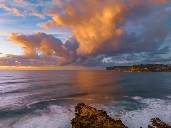 Sunrise and clouds over the ocean and rock platform