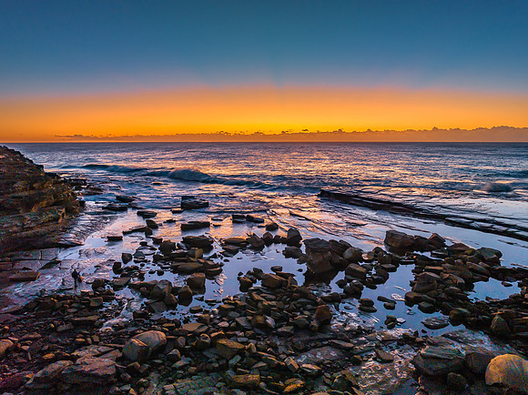 Sunrise over the sea and rocky Inlet with clear skies and a low