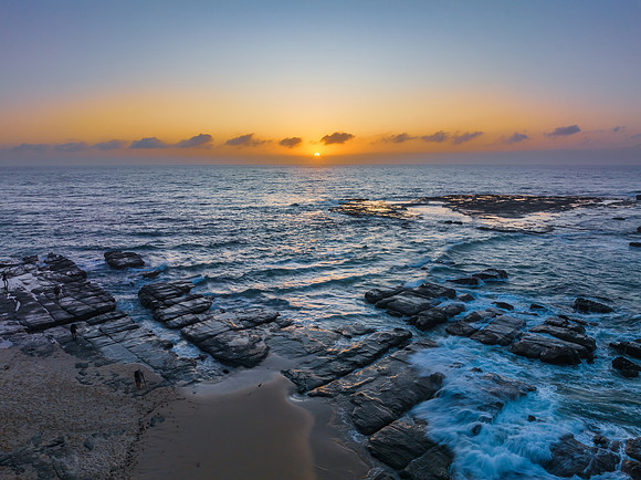 Aerial sunrise seascape with the sun, high tide and rock platfor