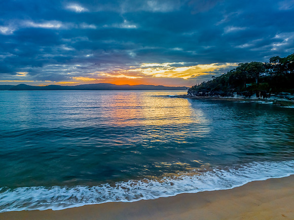 Aerial sunrise seascape with calm seas and a mix of high and low
