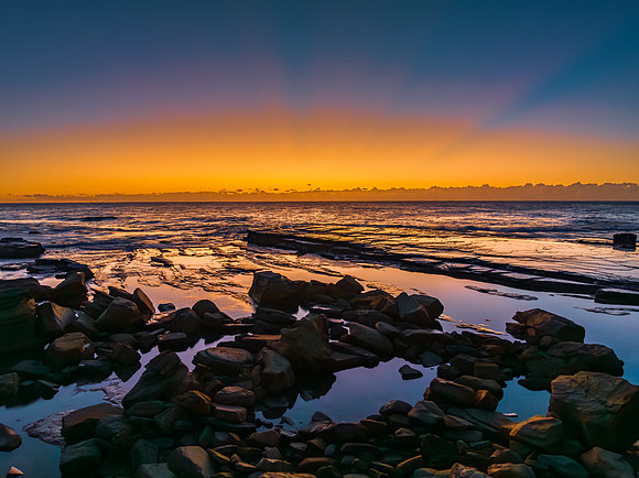 Sunrise over the sea and rocky Inlet with clear skies and a low