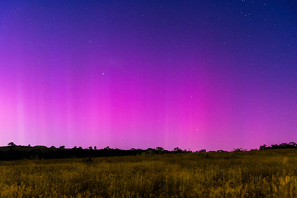 Aurora Australis display lights up the predawn sky in pinks