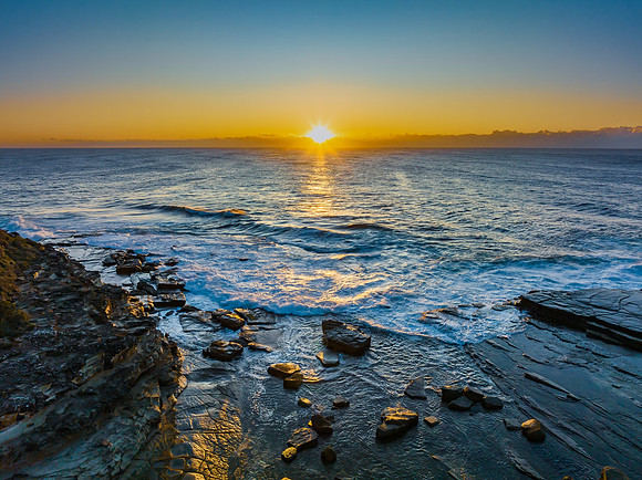 Sunrise over the sea and rocky Inlet with clear skies and a low