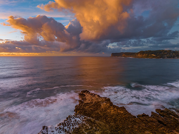 Sunrise and clouds over the ocean and rock platform