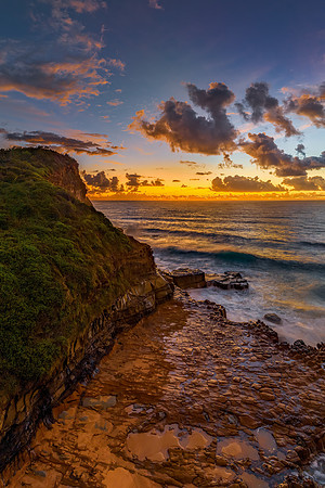 Sunrise and clouds over the ocean and rock platform