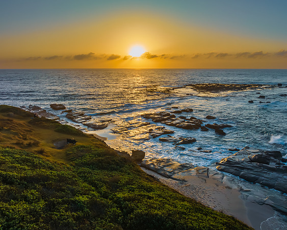 Aerial sunrise seascape with the sun, high tide and rock platfor