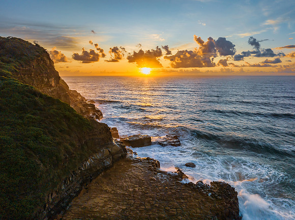 Sunrise and clouds over the ocean and rock platform