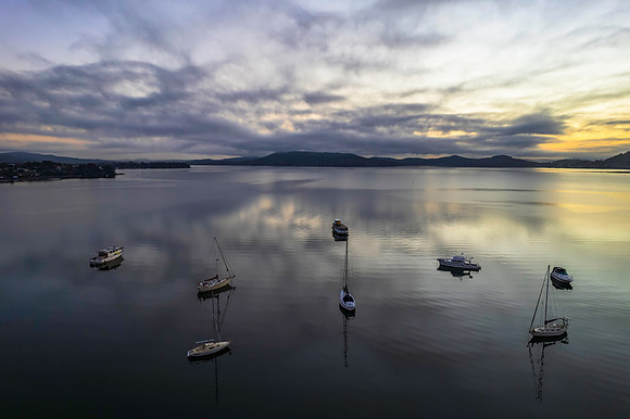 Sunrise waterscape with boats, soft clouds and reflections