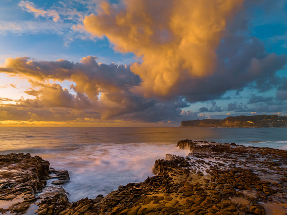 Sunrise and clouds over the ocean and rock platform