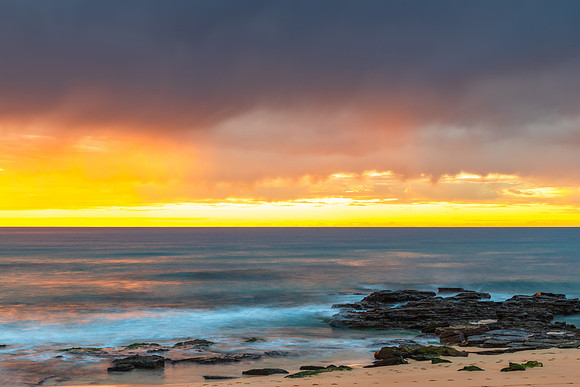 Winter sunrise by the sea shore with rain clouds
