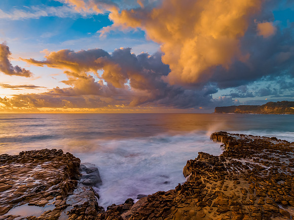 Sunrise and clouds over the ocean and rock platform