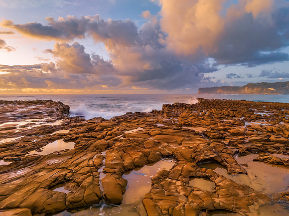 Sunrise and clouds over the ocean and rock platform