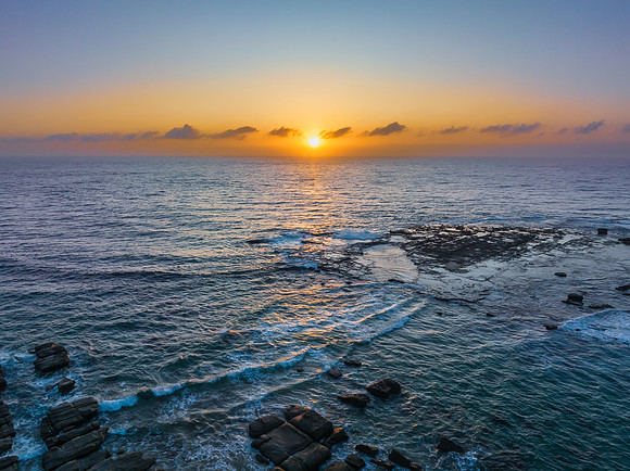 Aerial sunrise seascape with the sun, high tide and rock platfor