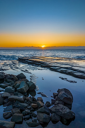 Sunrise over the sea and rocky Inlet with clear skies and sun pe