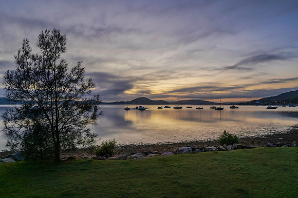 Sunrise waterscape with boats, soft clouds and reflections