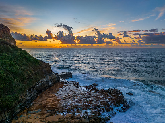 Sunrise and clouds over the ocean and rock platform