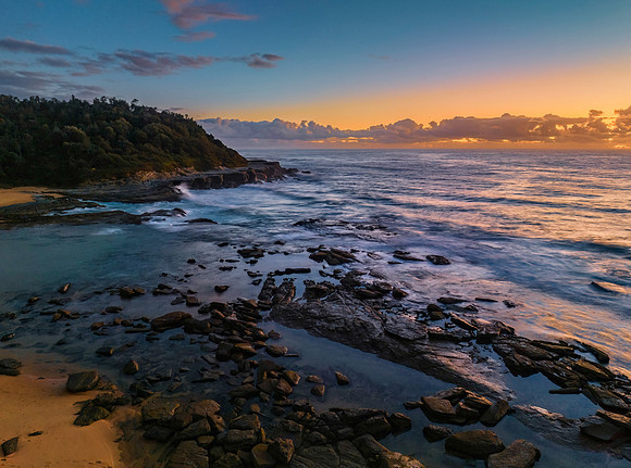Summer sunrise at the seaside with clouds and rocks