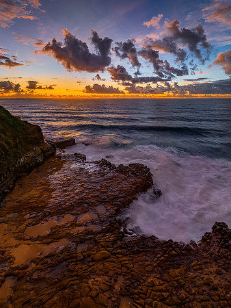 Sunrise and clouds over the ocean and rock platform