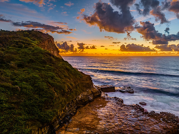 Sunrise and clouds over the ocean and rock platform