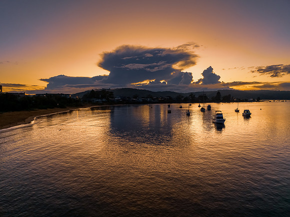 Aerial sunrise waterscape with scattered rain clouds, fog and bo