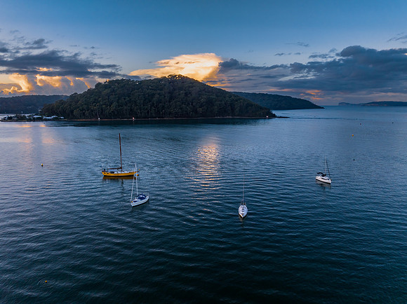 Aerial sunrise waterscape with scattered rain clouds, fog and bo