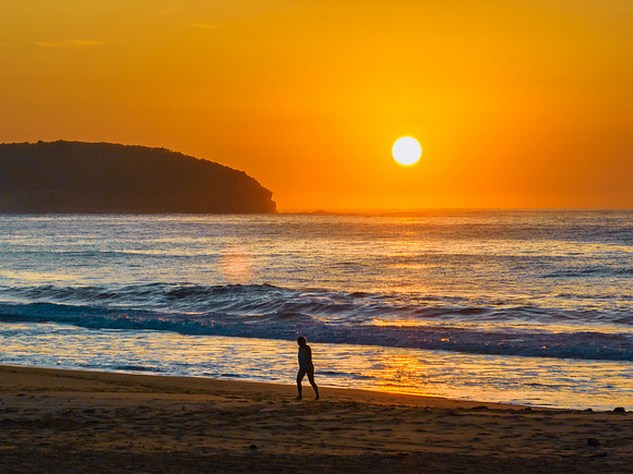 Soft hazy sunrise seascape, orange sky, people silhouettes and f