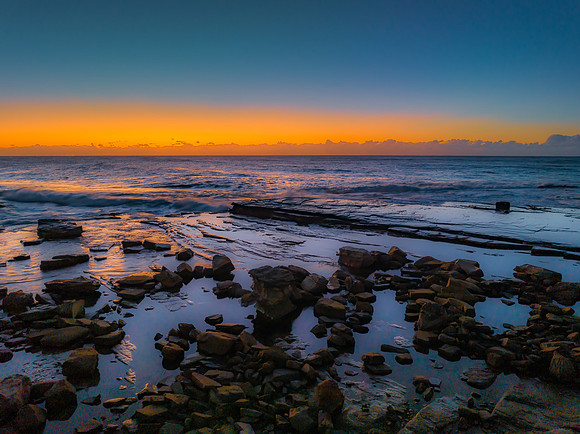 Sunrise over the sea and rocky Inlet with clear skies and a low