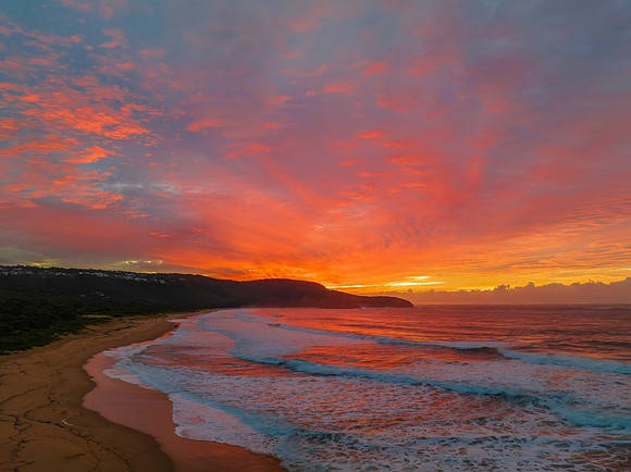 Cloud covered sunrise at the seaside in pink and blue