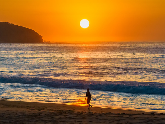 Soft hazy sunrise seascape, orange sky, woman silhouette and ful